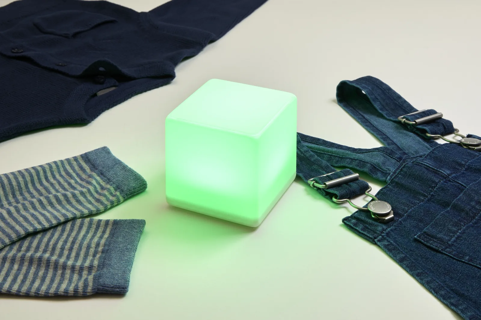 Un cube LittleCubes vert entouré de vêtements pour une routine d'habillage