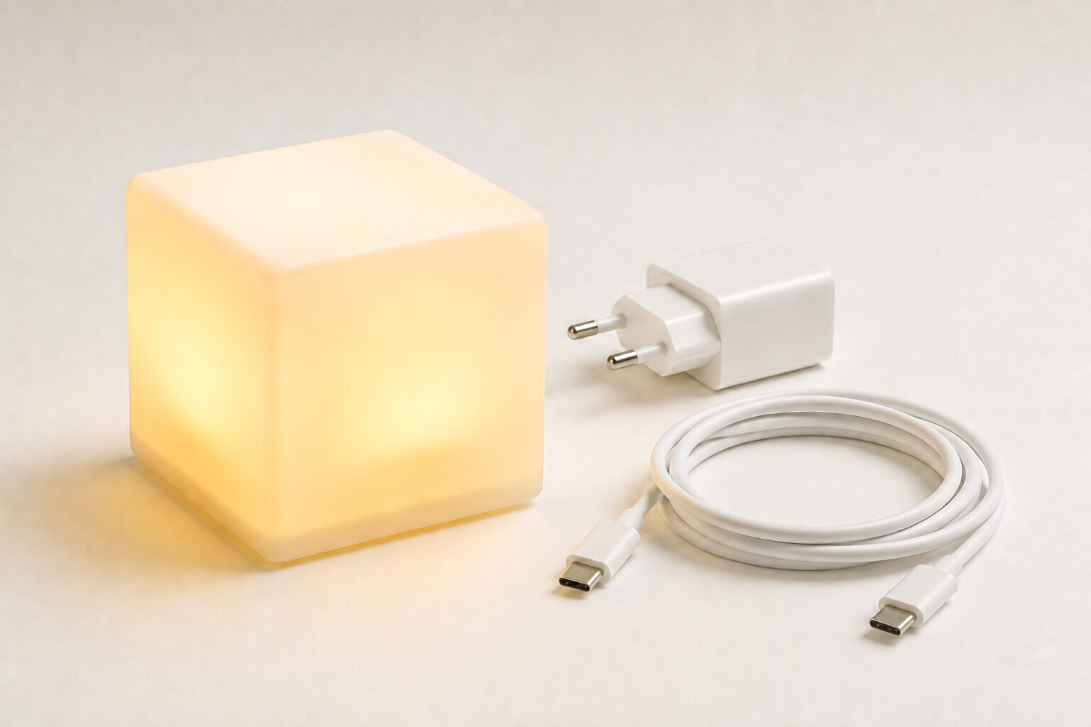 Un cube LittleCubes jaune, un chargeur et un câble USB-C avec ses deux extrémités visibles et débranchées