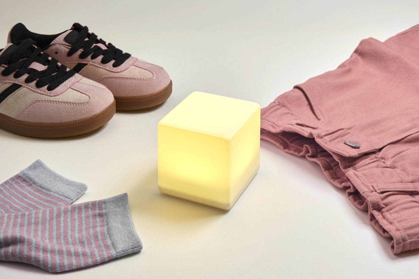 Le cube LittleCubes allumé à côté de chaussures et de vêtements d'enfant